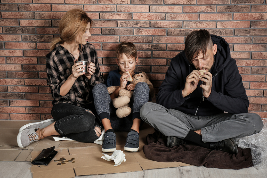 Poor Homeless Family Sitting on Floor near Brick Wall